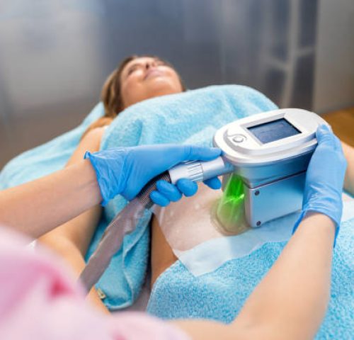 Beautician therapist applying cryolipolysis treatment in beauty salon.